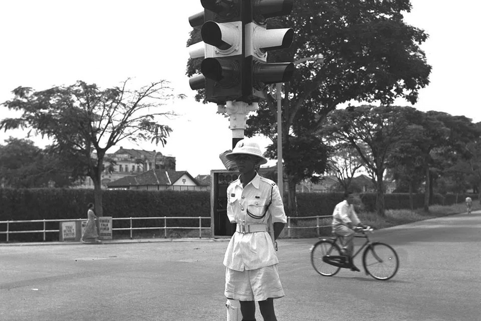 Seorang pegawai polis trafik berdiri di tengah-tengah jalan raya semasa melaksanakan tugas sewaktu Hari Raya Aidilfitri pada Julai 1957. 
