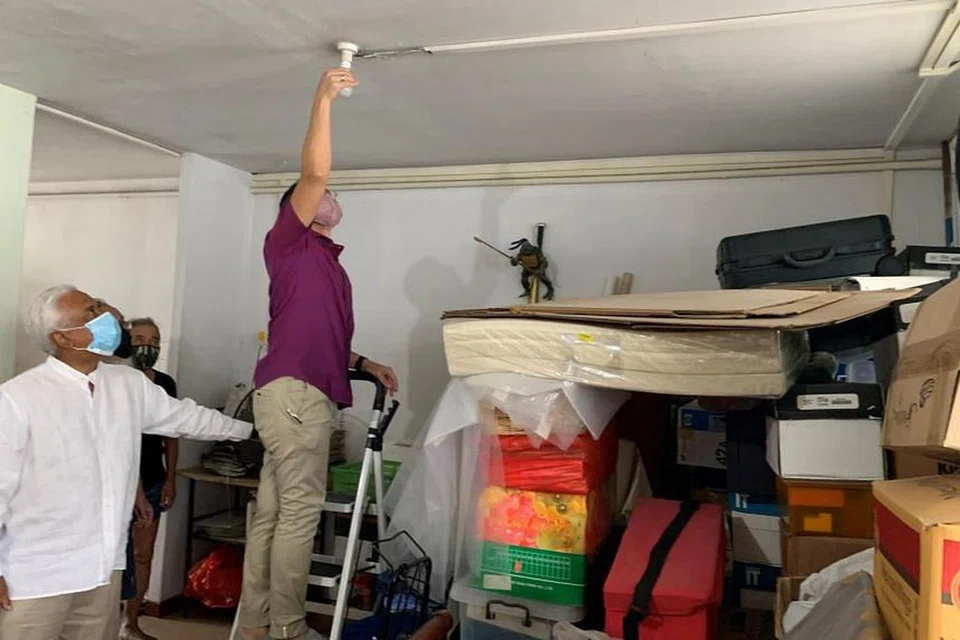 BANTU JIMAT ELEKTRIK: Dr Maliki membantu mengubah bal lampu LED yang menjimat tenaga di rumah Encik Yeo. - Foto PEJABAT KAWASAN UNDI SIGLAP 