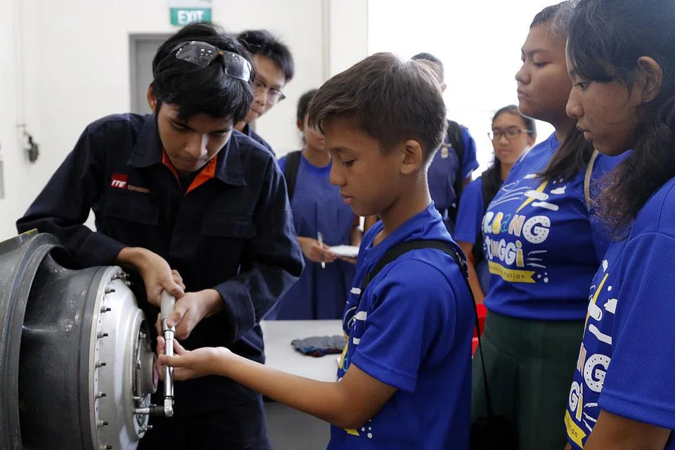 LATIHAN AMALI: Pelajar daripada Sekolah Menengah Greenview, Alif Al Matin Mohammad Azhar (tengah), sedang mempelajari cara bagaimana enjin kapal terbang diselenggarakan. - Foto FARAH REZAL
