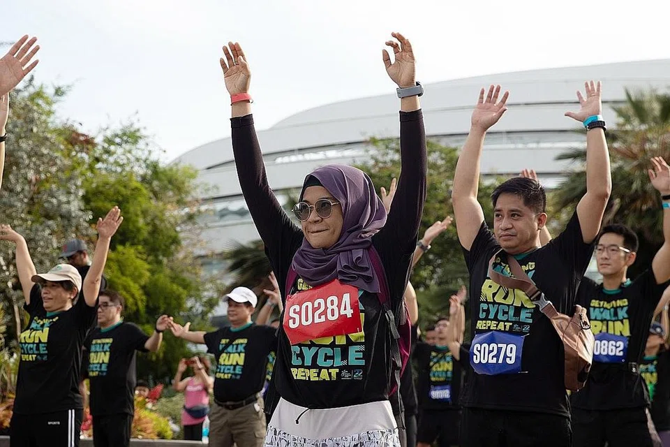 SEMUA ANGKAT TANGAN!: Cik Nadia (kiri) dan rakan-rakan 'warm up' sebelum acara bermula. - Foto NHG