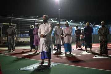 BOLEH SOLAT BERJEMAAH: Pekerja migran dan imam, Encik Ullah Mohammad Aman, memimpin solat isyak dan tarawih yang diadakan di gelanggang bola keranjang di dormitori di Choa Chua Kang Grove. Baru-baru ini, MOM mengumumkan dormitori dibenarkan mengadakan dua sesi solat berjemaah untuk hingga 200 orang sepanjang Ramadan ini, dengan langkah-langkah keselamatan seperti menggunakan pelitup dan jarak satu meter antara setiap jemaah dilaksanakan. - Foto BM oleh ARIFFIN JAMAR 