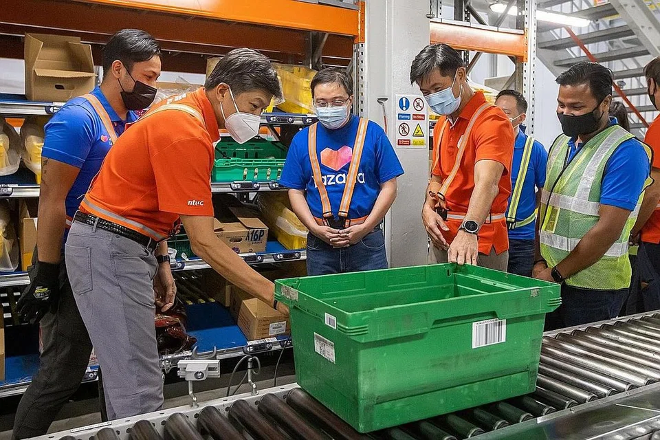 TINGKATKAN KEMAHIRAN PEKERJA: (Dua dari kiri) Encik Ng bersama, Ketua Pegawai Eksekutif Lazada Singapura Encik Loh Wee Lee (tiga dari kiri) dan Timbalan Setiausaha Agung NTUC Encik Desmond Tan (empat dari kiri) di stesen Pick-to-Light semasa lawatan gudang. - Foto-foto NTUC