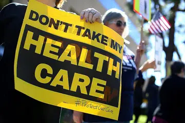 BANTAHAN PELAN INSURANS BARU: Penunjuk perasaan yang membantah tindakan menarik balik pelan insurans Obamacare mengadakan bantahan di luar pejabat ahli kongres Republikan, Encik Darryl Issa, di Vista, California, semalam. - Foto REUTERS