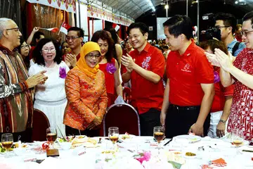 SOKONGAN PADU: Cik Halimah mendapat tepukan gemuruh selepas mengumumkan akan bertanding dalam Pilihan Raya Presiden malam tadi. Turut bersama beliau ialah suaminya, Encik Mohammed Abdullah Alhabshee (kiri) dan AP-AP GRC Marsiling-Yew Tee lain termasuk (dari kanan) Encik Ong Teng Koon, Encik Alex Yam dan Encik Lawrence Wong. - Foto KHALID BABA