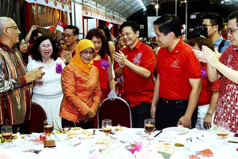 SOKONGAN PADU: Cik Halimah mendapat tepukan gemuruh selepas mengumumkan akan bertanding dalam Pilihan Raya Presiden malam tadi. Turut bersama beliau ialah suaminya, Encik Mohammed Abdullah Alhabshee (kiri) dan AP-AP GRC Marsiling-Yew Tee lain termasuk (dari kanan) Encik Ong Teng Koon, Encik Alex Yam dan Encik Lawrence Wong. - Foto KHALID BABA