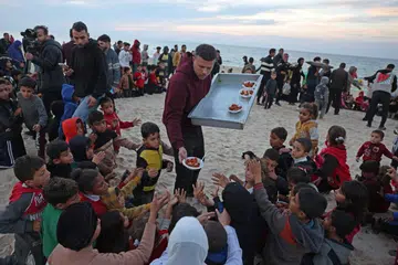 Encik Hamada Shaqoura, yang dahulunya seorang ‘blogger’ makanan, mengagihkan makanan kepada kanak-kanak selepas menyediakan hidangan untuk mangsa kehilangan tempat tinggal di Khan Yunis, selatan Jaluran Gaza pada 16 Januari 2025. 
