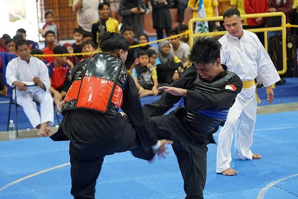 TUNJUK TARING: Ahmad Hanin (kanan) dari Singapura beraksi ketika menentang Muhammad Adam daripada pasukan Kedah Fighter dalam pusingan saringan Tanding Putera D semalam. - Foto PERSEKUTUAN SILAT SINGAPURA