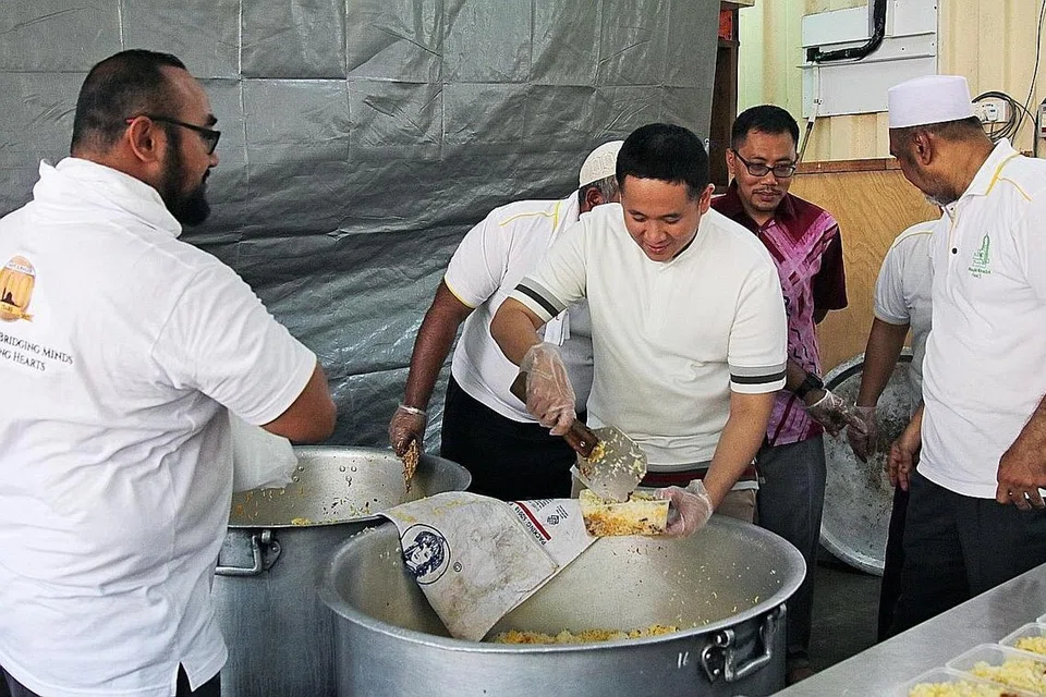 BERIANI AMAL: Encik Amrin (tengah) membantu kakitangan Masjid Khalid membungkus nasi beriani untuk jualan amal MCS. - Foto BH oleh JEREMY KWAN