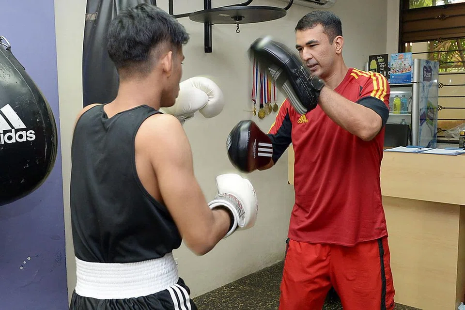 BANTU BELIA FOKUS DAN BERMATLAMAT: Encik Mohamed Zafar Hussein Malik (kanan) memastikan belia seperti Encik Muhammad Muslihin Omar ada arah tuju dan dapat digarap kemahiran bertinjunya di pusat kecergasan Boxfit Gym Singapore. - Foto TUKIMAN WARJI