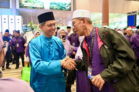 Pemangku Menteri Bertanggungjawab bagi Ehwal Masyarakat Islam, Profesor Madya Dr Muhammad Faishal Ibrahim (kiri), beramah-tamah dengan anggota jemaah yang bakal menunaikan ibadah haji di Terminal 3 Lapangan Terbang Changi pada 13 Mei.
