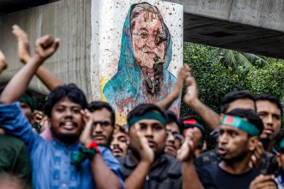 Para pelajar melaungkan slogan berhampiran mural bekas Perdana Menteri Bangladesh, Sheikh Hasina, yang dirosakkan ketika mereka mengadakan bantahan menuntut perbicaraan terhadap Hasina, berhampiran Universiti Dhaka. 