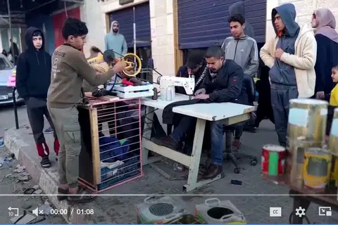 IDEA KREATIF: Tukang jahit Palestin, Encik Majed Abu Hajeb (duduk), menjahit pakaian dan terpaksa menggunakan mesin jahit usangnya dengan anaknya, Magdy (dua dari kiri), memutarkan pedal basikal yang telah diubah suai untuk menggerakkan mesin jahitnya.