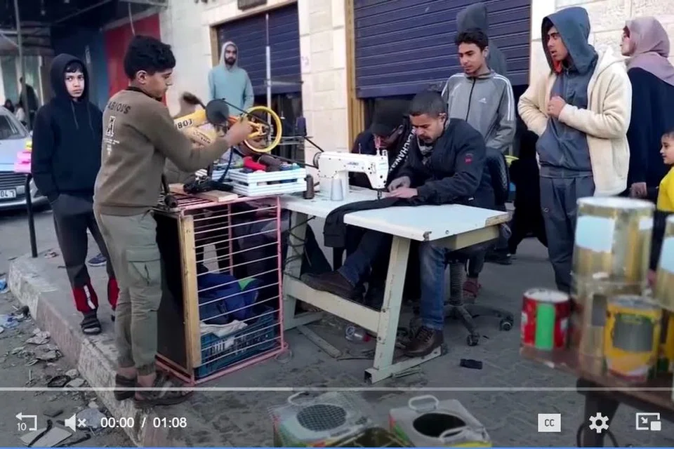 IDEA KREATIF: Tukang jahit Palestin, Encik Majed Abu Hajeb (duduk), menjahit pakaian dan terpaksa menggunakan mesin jahit usangnya dengan anaknya, Magdy (dua dari kiri), memutarkan pedal basikal yang telah diubah suai untuk menggerakkan mesin jahitnya.