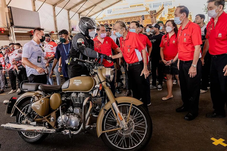 BERMOTOSIKAL DEMI AMAL: Encik Wong (kiri, bertopi keledar), yang turut menunggang motosikal secara berkonvoi, bersalaman dengan Pengerusi Loyang Tua Pek Kong, Encik George Peh, sebaik tiba di acara amal sempena menyambut Hari Kebangsaan dan Hari Keharmonian Kaum anjuran Kumpulan Riders Aid Singapore semalam. - Foto BH oleh NUR DIYANA TAHA