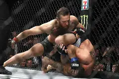 PAMER KETANGKASAN: Pengadil Herb Dean bertindak menamatkan pertarungan itu sekitar 40 saat dalam pusingan pertama antara Conor McGregor (menghayun tumbukan) dan Donald "Cowboy" Cerrone di T-Mobile Arena di Las Vegas. - Foto AFP