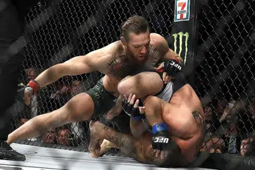 PAMER KETANGKASAN: Pengadil Herb Dean bertindak menamatkan pertarungan itu sekitar 40 saat dalam pusingan pertama antara Conor McGregor (menghayun tumbukan) dan Donald "Cowboy" Cerrone di T-Mobile Arena di Las Vegas. - Foto AFP