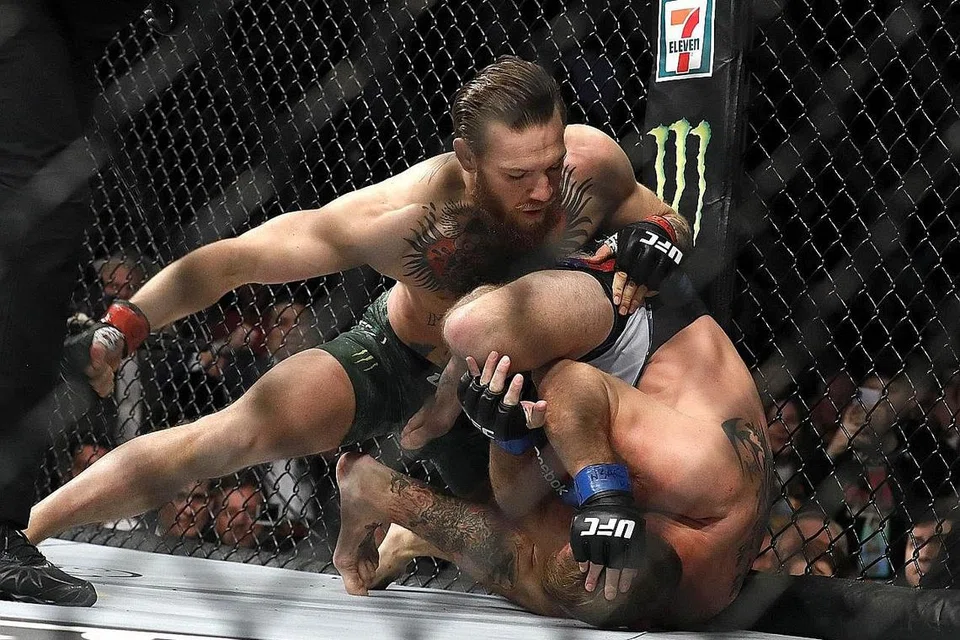 PAMER KETANGKASAN: Pengadil Herb Dean bertindak menamatkan pertarungan itu sekitar 40 saat dalam pusingan pertama antara Conor McGregor (menghayun tumbukan) dan Donald "Cowboy" Cerrone di T-Mobile Arena di Las Vegas. - Foto AFP