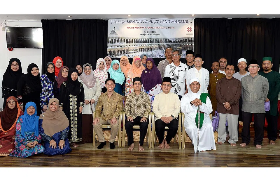 MENYERIKAN ACARA: Profesor Madya Muhammad Faishal Ibrahim (duduk di kerusi, dua dari kiri) bergambar bersama penduduk Yishun dan Kebun Baru yang bakal menunaikan ibadah haji di Masjid Darul Makmur semalam. - Foto JOHARI RAHMAT