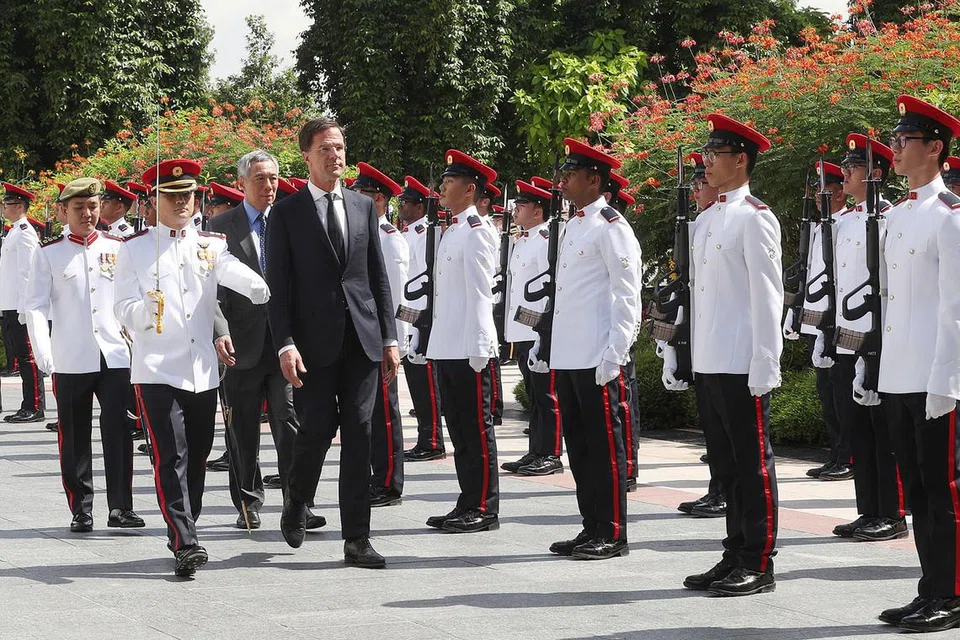 SAMBUTAN PENUH HORMAT: Encik Rutte (berkot, depan) disambut dengan penuh istiadat semasa mengadakan lawatan rasmi sehari ke Singapura semalam. Mengiringi beliau di upacara barisan kehormat ialah Perdana Menteri Lee (di belakang Encik Rutte). - Foto THE STRAITS TIMES