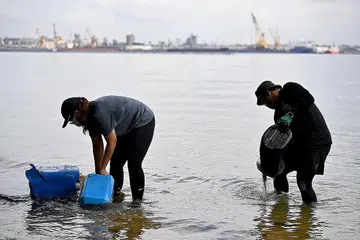 PANTAI BERSIH: Relawan SG Beach Warriors, Cik Nurasylah (kiri) dan Encik Irsyad, membersihkan tong air yang tertimbus dalam pasir untuk dikumpulkan sebagai sampah yang dikutip dalam sesi pembersihan pantai. - Foto BM oleh LIM YAOHUI