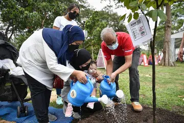 DETIK MANIS: Encik Masagos Zulkifli Masagos Mohamad (kanan) membantu menanam pokok bersama keluarga Encik Mohd Dzulhilmy Masni (tiada dalam gambar) dan Cik Syasya Firzana Rosle (tudung hitam) bagi memperingati kelahiran anak mereka, Miiya Dzafirah, dua tahun. - Foto BM oleh ARIFFIN JAMAR