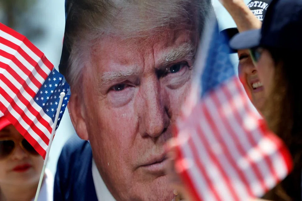 Seorang penyokong Encik Donald Trump, memegang potret bekas Presiden Amerika itu, semasa demonstrasi sehari selepas beliau ditembak dalam cubaan membunuh semasa perhimpunan di Pennsylvania, di Huntington Beach, California, pada 14 Julai 2024. 