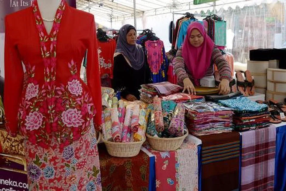 MALAYSIA BOLEH: Cik Aliah Abdullah (kanan) dan Cik Nur Hayati Mat Zaini sibuk mempamerkan pakaian tradisi Malaysia untuk pelanggan. - Foto TUKIMAN WARJI