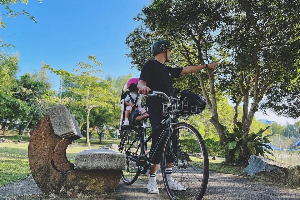 TEROKA BERSAMA ANAK DENGAN BASIKAL: Penulis bersama anaknya (dibonceng di belakang) di taman Pasir Ris Town Park dengan basikal khas bagi kegiatan itu. - Foto BH oleh HARITH MUSTAFFA