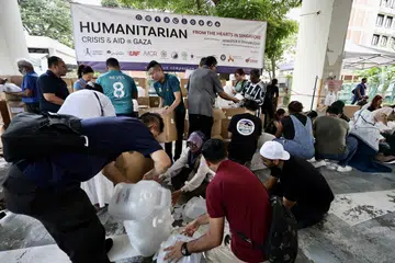 GOTONG-ROYONG: Relawan yang berhimpun di sebuah bangunan perindustrian di Geylang pada Ahad kelihatan membungkus barang keperluan dalam kotak-kotak yang akan diagihkan kepada mangsa di Gaza. 