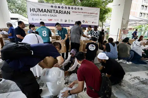GOTONG-ROYONG: Relawan yang berhimpun di sebuah bangunan perindustrian di Geylang pada Ahad kelihatan membungkus barang keperluan dalam kotak-kotak yang akan diagihkan kepada mangsa di Gaza. 
