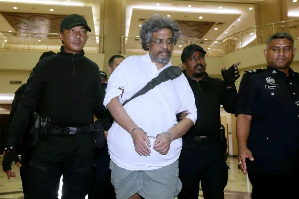 Pastor sambilan, N Deanesh, 53 tahun (tangan digari), didakwa di Mahkamah Majistret Kuala Lumpur pada 26 November atas tuduhan membunuh ibunya sebelum menyumbat dan menyimpan mayat mangsa dalam peti sejuk beku selama tiga tahun pada 2021.