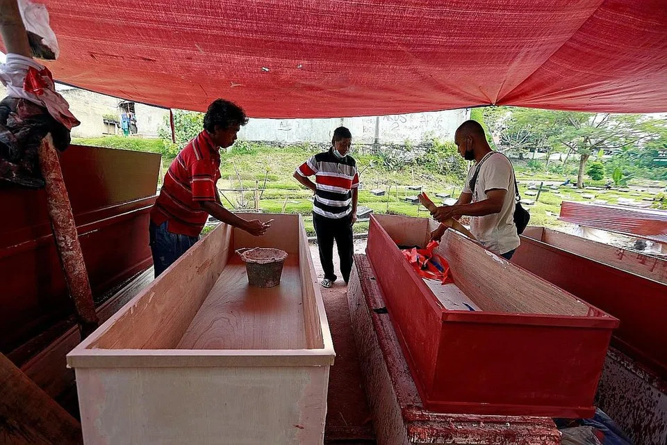 TEMPAHAN KERANDA MENINGKAT: Pembuat keranda di Jakarta sibuk berusaha memenuhi tempahan di tengah-tengah lonjakan kematian akibat jangkitan Covid-19 di Indonesia. - Foto REUTERS