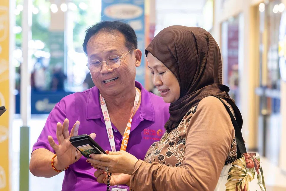 Seorang duta digital dari Pejabat Digital SG (SDO) berinteraksi dengan seorang pengguna telefon bijak. Duta-duta dari SDO dan pelajar membentuk tenaga relawan yang memberi bimbingan kepada warga yang mengalami cabaran menggunakan teknologi, seperti menebus baucar CDC menerusi telefon bimbit, membuat panggilan video dan sebagainya. 