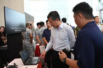 Menteri Pertahanan, Encik Chan Chun Sing (dua dari kanan), menyaksikan demonstrasi Teknologi Sistem Udara Berbilang Kawalan Kos Rendah (Locust) yang dikendalikan Agensi Sains dan Teknologi Pertahanan (DSTA) pada 16 Julai.
