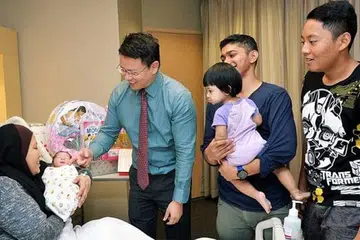 BAYI SG50: Cik Anisah (mendukung Adam Hariz) dan Encik Muhd Hafiz (mendukung Qurratu Ain Al-Adhawiyah) - bersama seorang lagi anak mereka, Muhd Aiman Nifail (kanan). Bersama mereka ialah Dr Jazlan. - Foto KHALID BABA