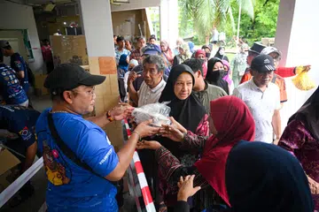 USAHA AMAL: Para penduduk menerima pek beriani percuma di 536 Bedok North Street 3 pada pagi Ahad.