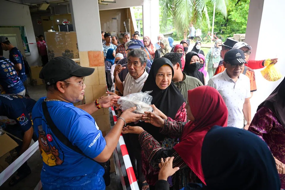 USAHA AMAL: Para penduduk menerima pek beriani percuma di 536 Bedok North Street 3 pada pagi Ahad.