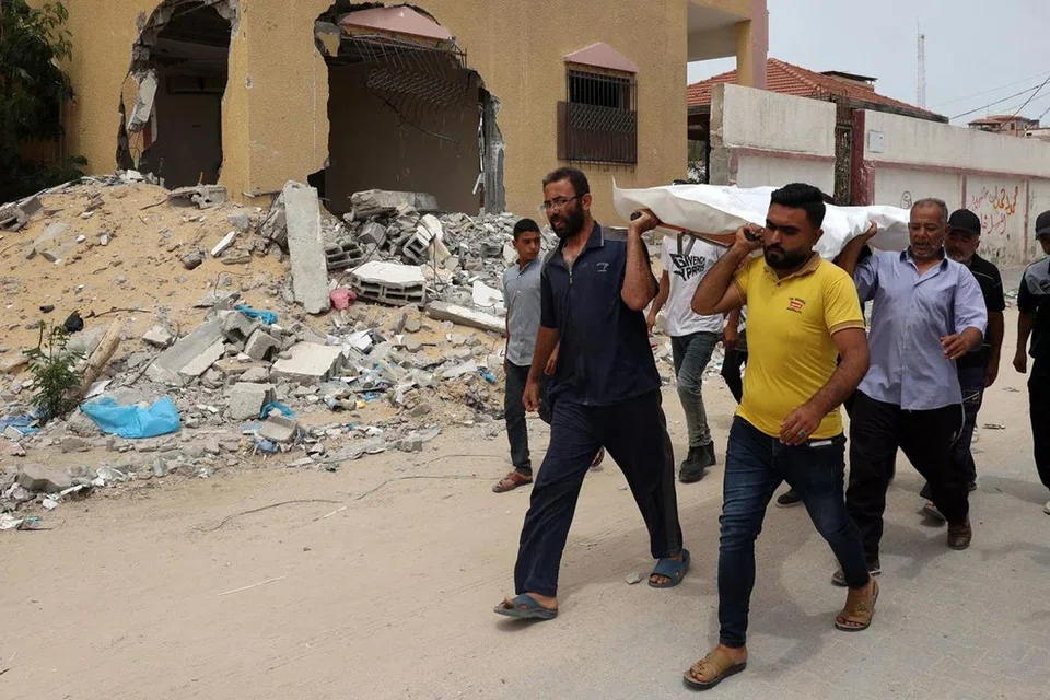 
Orang ramai mengusung jenazah selepas dikenal pasti. Jenazah itu adalah   antara ratusan mayat yang ditemui dan digali dari kubur besar yang ditemui di Hospital Nasser di selatan Jaluran Gaza.