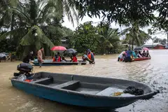 Orang ramai menggunakan bot untuk melalui kawasan banjir di Kuala Terengganu, Malaysia. Di Terengganu, pihak berkuasa menyatakan jumlah penduduk yang berlindung di 112 pusat pemindahan sementara (PPS) menurun kepada 15,243 mangsa berbanding 20,552 mangsa pada Jumaat malam, 