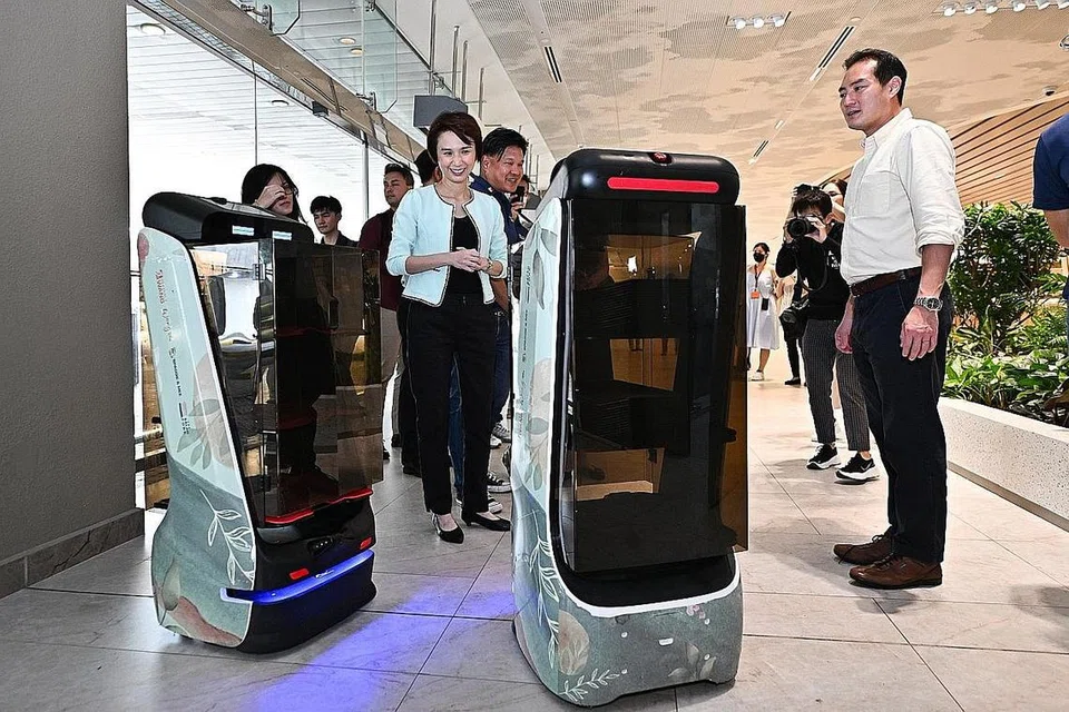 LIHAT ROBOT BEKERJA: Menteri Negara (Perdagangan dan Perusahaan), Cik Low Yen Ling, dan Menteri Negara Kanan (Perhubungan dan Penerangan), Encik Tan Kiat How, melihat Robot Penyampaian Perkhidmatan di Heavenly Wang, sebuah syarikat yang meraih manfaat daripada Pelan Digital Industri (IDP) di Terminal 2 Lapangan Terbang Changi semalam.- Foto BH oleh LIM YAOHUI
