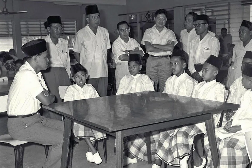 KUNJUNGAN SAYANG: Encik Othman (kiri) beramah mesra dengan penghuni Rumah Anak Yatim Darul Ihsan di Mattar Road pada 1964. - Foto fail 