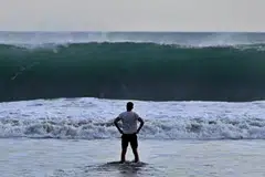 Seorang pengunjung pantai melihat ombak besar di pantai Kuta berhampiran Denpasar, pulau Bali di Indonesia.