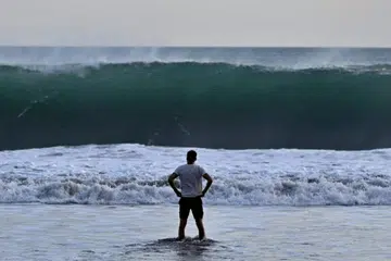 Seorang pengunjung pantai melihat ombak besar di pantai Kuta berhampiran Denpasar, pulau Bali di Indonesia.