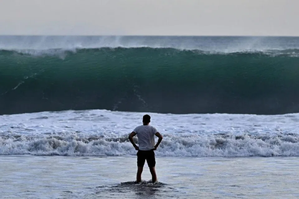 Seorang pengunjung pantai melihat ombak besar di pantai Kuta berhampiran Denpasar, pulau Bali di Indonesia.