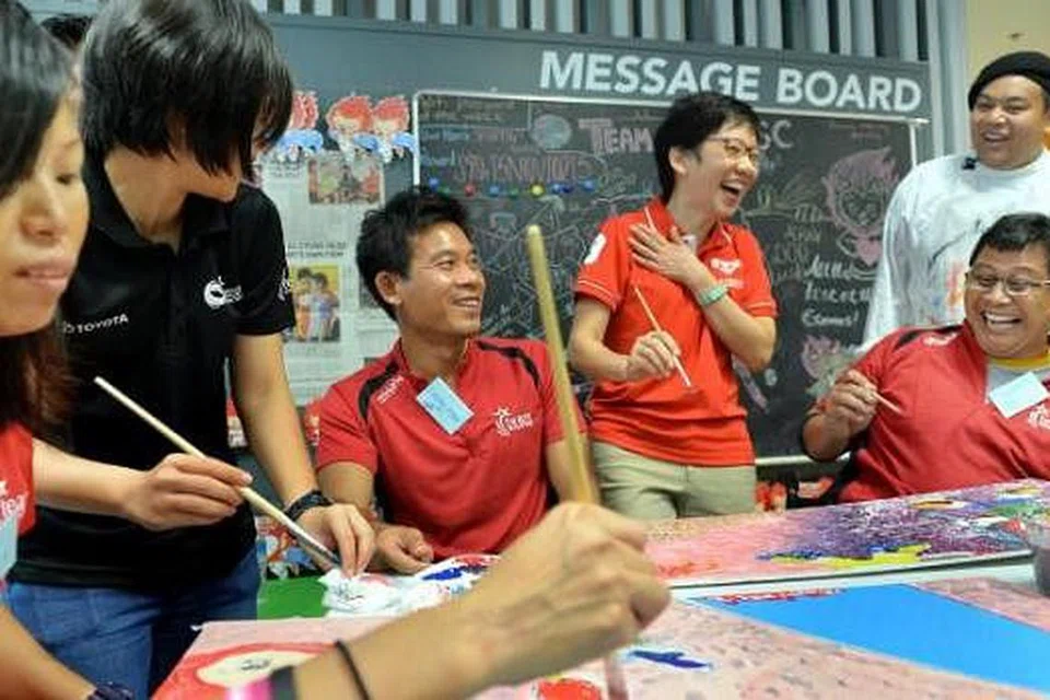 BERI SOKONGAN: Cik Fu (tiga dari kanan) berkongsi saat lucu dengan atlit Team Singapore di acara melukis di perkhemahan Team Singapore semalam. - Foto-foto M.O. SALLEH.