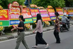 Pejalan kaki melintasi papan ucapan tahniah kepada calon pemimpin Jakarta, Encik Pramono Anung dan Encik Rano Karno, yang setakat ini mendahului keputusan pilihan raya Gabenor Jakarta berdasarkan kiraan pantas, di Jakarta pada 29 November. 