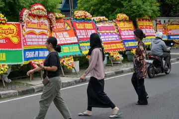 Pejalan kaki melintasi papan ucapan tahniah kepada calon pemimpin Jakarta, Encik Pramono Anung dan Encik Rano Karno, yang setakat ini mendahului keputusan pilihan raya Gabenor Jakarta berdasarkan kiraan pantas, di Jakarta pada 29 November. 