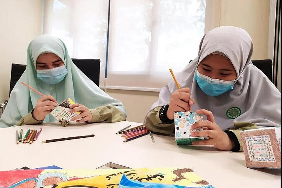 KARYA SENI: Pelajar menengah dua MAI, Salwa Sanaullah Khan (kiri) dan Nur Sumayyah Mohammad Zaki (kanan) menggunakan bahan mewarna kering - pensel warna, krayon dan penanda untuk mereka karya seni Cube Art. - Foto MAI