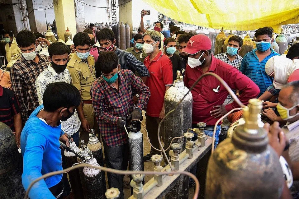 KEPERLUAN GENTING: Orang ramai berpusu-pusu mengisi semula balang gas oksigen bagi keperluan pesakit Covid-19 di pusat pengisian semula oksigen di Allahabad, India. - Foto AFP