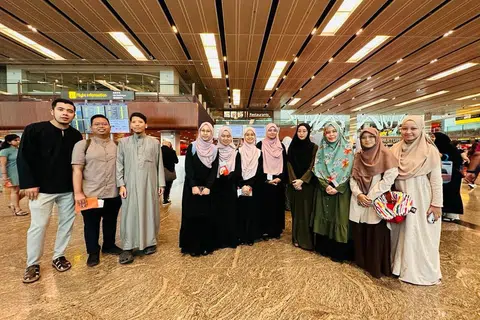 BERLPAS: Pasukan Singapura Kejohanan Debat Sekolah Antarabangsa Qatar 2023 (tengah, berbaju hitam) bergambar dengan jurulatih dari Munazarah SG di Lapangan Terbang Changi.
